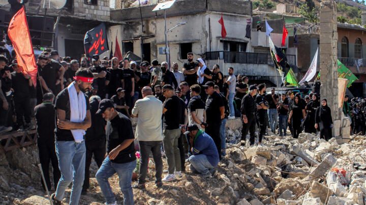 Shiite worshippers walk past the rubble of buildings destroyed by previous Israeli strikes during a religious procession in Kfarkila in southern Lebanon on July 5, 2025.