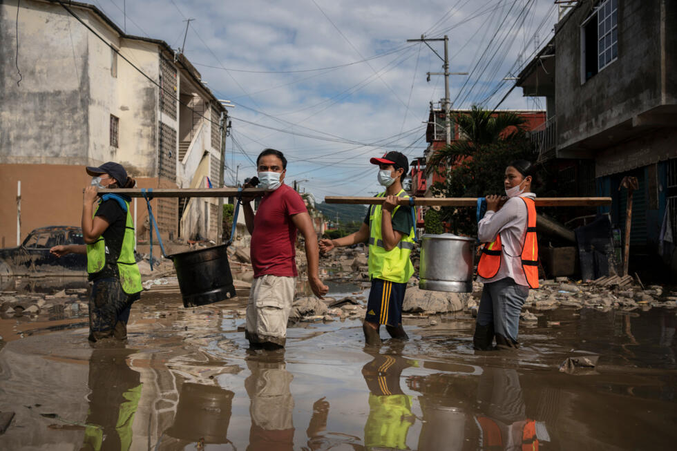 Un grupo de personas traslada ollas con tamales donados por voluntarios para atender a los damnificados por las torrenciales lluvias en Veracruz. 15 de octubre de 2025.