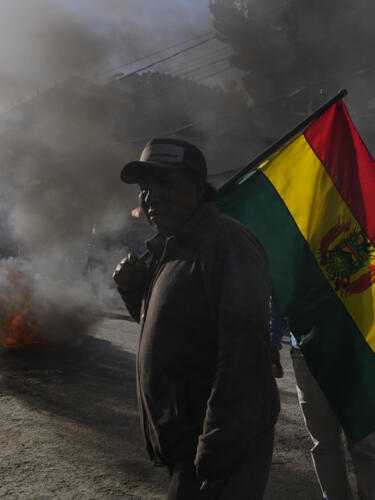 Un agricultor de hoja de coca lleva una bandera boliviana durante los enfrentamientos cerca del mercado de coca en La Paz, Bolivia, el lunes 1 de agosto de 2022. Los cocaleros antigubernamentales están protestando contra un nuevo mercado de hoja de coca en La Paz. (AP Foto/Juan Karita)