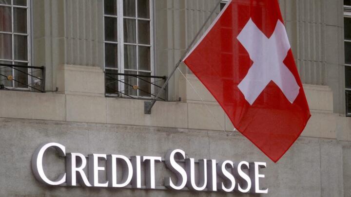 The national flag of Switzerland flies over a logo of the Swiss bank Credit Suisse in front of a branch in Bern, Switzerland, November 29, 2022.