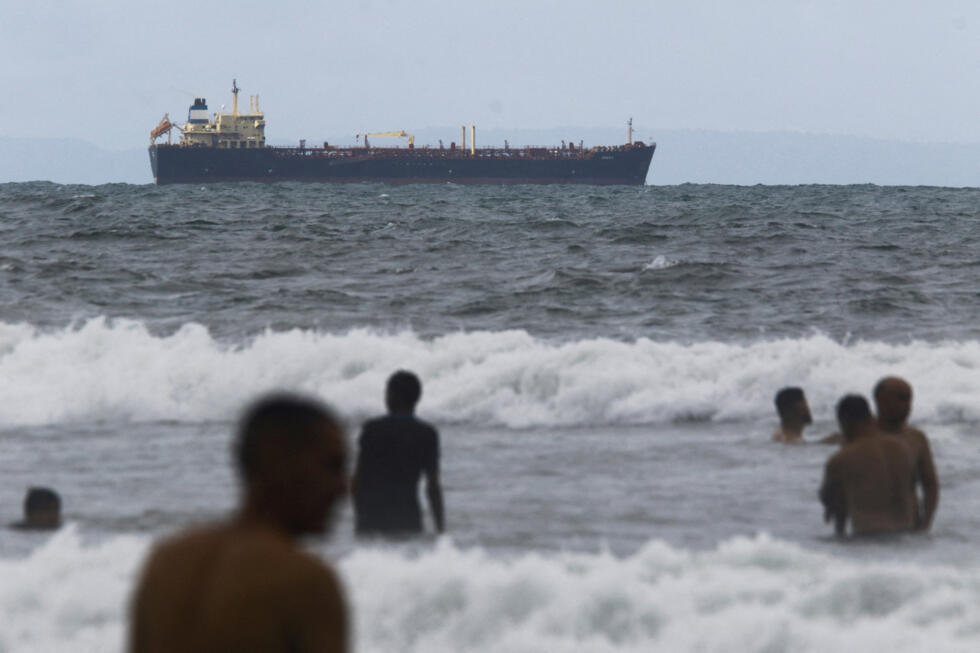 Mensen genieten van de oceaan nabij de onder Comoren vlag varende olietanker Evana, die olie vervoerde tussen binnenlandse havens in Venezuela, vlakbij de El Palito-terminal in Puerto Cabello, Venezuela.