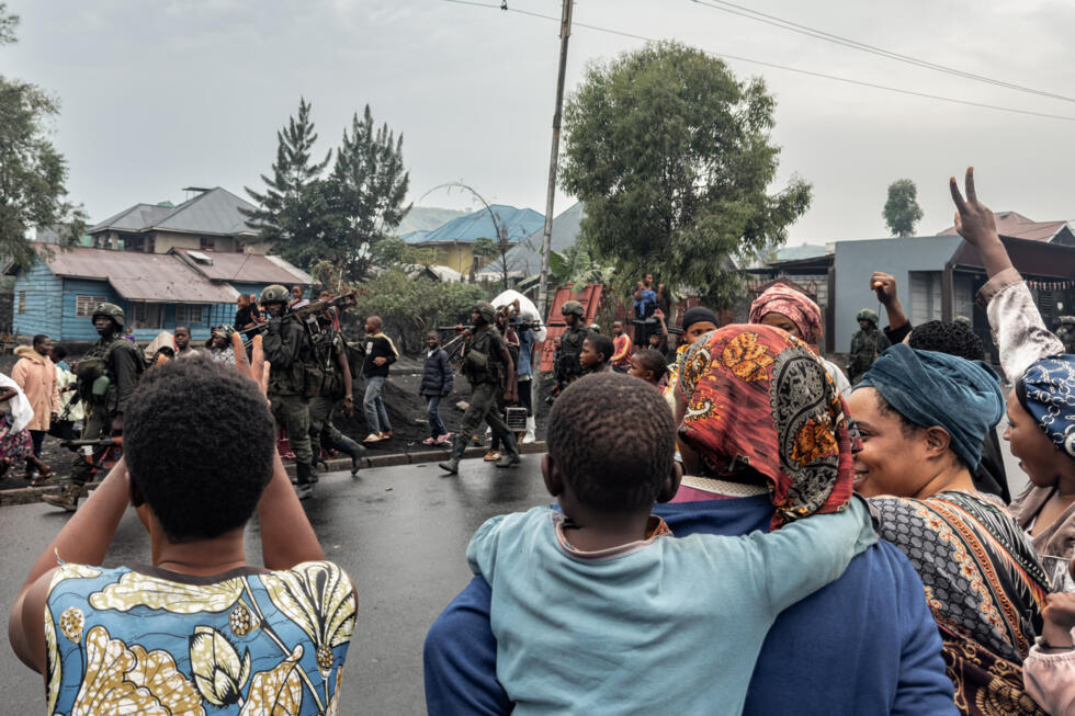 Des habitants réagissent alors que des membres du M23 marchent dans une rue du quartier de Keshero à Goma, le 27 janvier 2025 en RD Congo.
