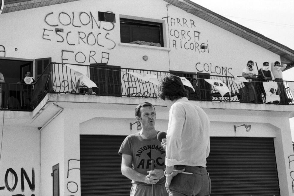 Edmond Simeoni (g), interviewé par un journaliste devant une cave viticole, pendant une trêve lors d'une prise d'otagesà Aléria, le 22 août 1975 en Haute-Corse