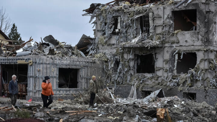People stand near a building hit during the Russian missile and drone strike in the town of Slobozhanske, Dnipro region.