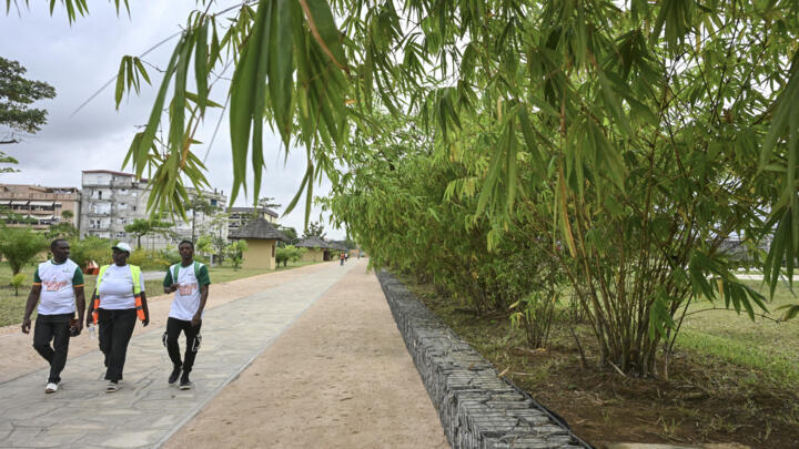 Pedestrians walk at the former Akouedo landfill that has now been turned into a park in Abidjan on August 1, 2025.