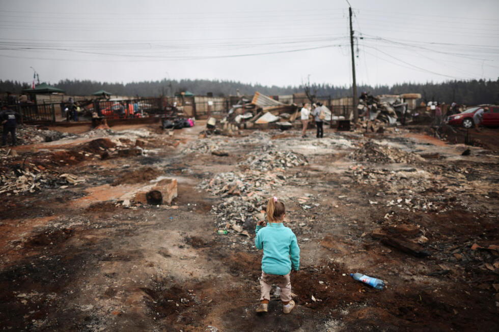Una niña juega entre los escombros después de que su casa fuera destruida por un incendio forestal en la región del Biobío, donde múltiples incendios forestales provocaron evacuaciones de emergencia, en Punta de Parra, Chile, el 20 de enero de 2026.