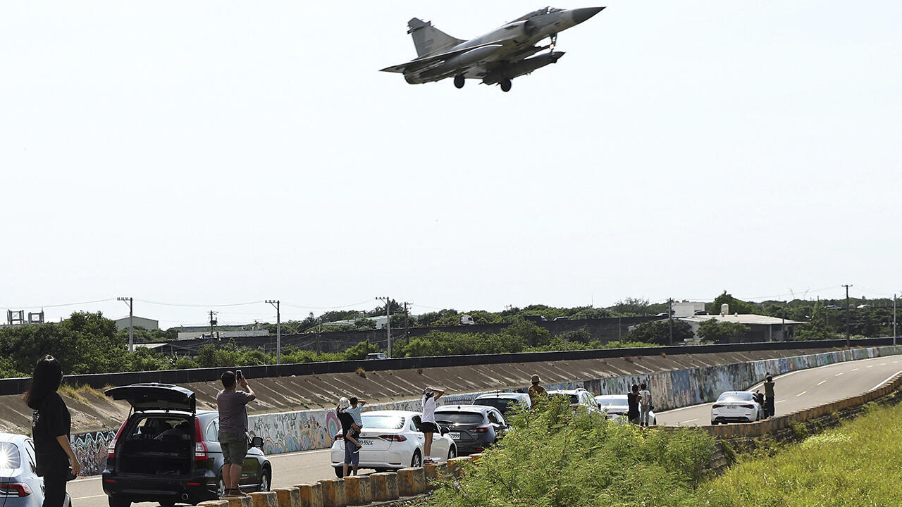 La gente observa cómo un avión Mirage 2000-5 de la Fuerza Aérea de Taiwán aterriza en la base aérea de Hsinchu en Hsinchu, el 7 de agosto de 2022.
