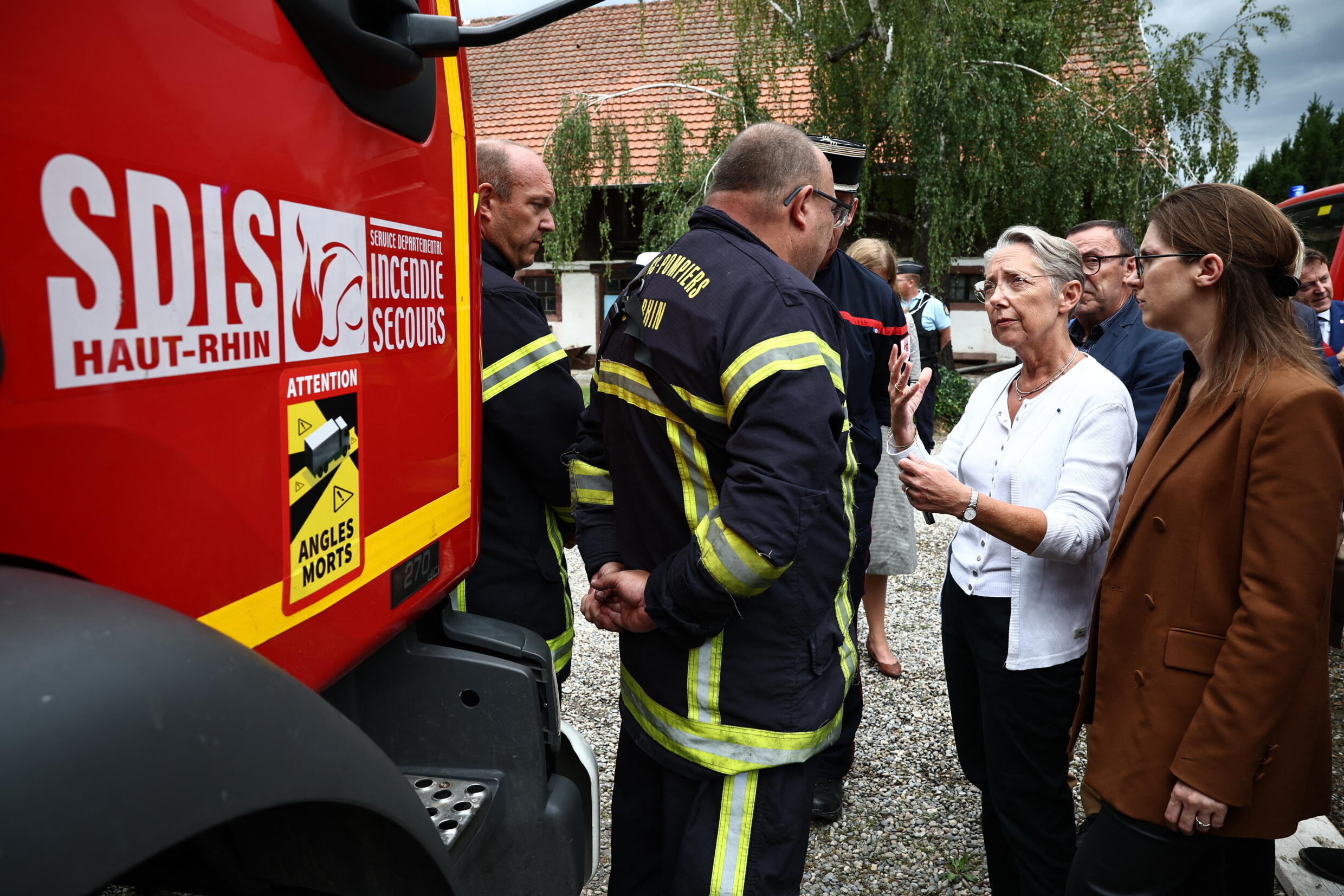 La primera ministra francesa, Elisabeth Borne (segunda a la derecha), habla con un bombero que participa en las operaciones de rescate tras el incendio declarado en una residencia de vacaciones para discapacitados en Wintzenheim, este de Francia, el 9 de agosto de 2023. Las autoridades encontraron nueve cadáveres después de que un incendio arrasara un centro de vacaciones para adultos con dificultades de aprendizaje en el este de Francia, informaron los bomberos.