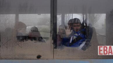 Un niño saluda mientras sale en un autobús de evacuación, tras la retirada militar rusa de Kherson, en la estación central de autobuses de Kherson, Ucrania 24 de noviembre de 2022.