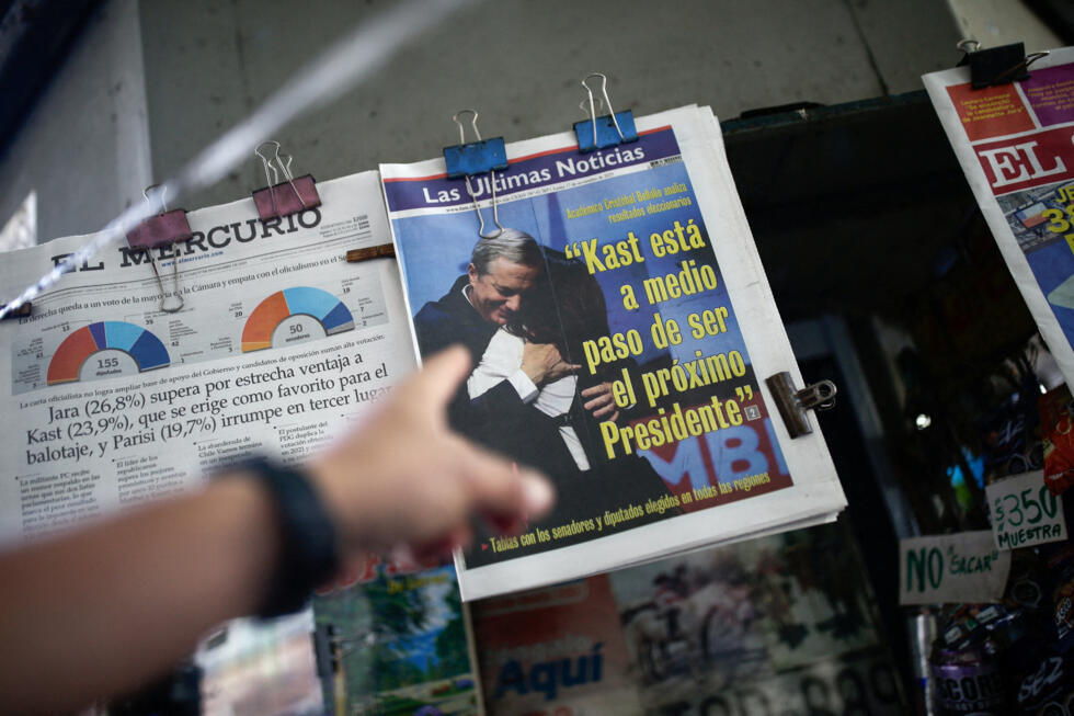 Un hombre señala un periódico  candidato presidencial de extrema derecha José Antonio Kast y un titular que dice "Kast está a medio camino de convertirse en el próximo presidente"en Santiago de Chile, el 17 de noviembre de 2025.