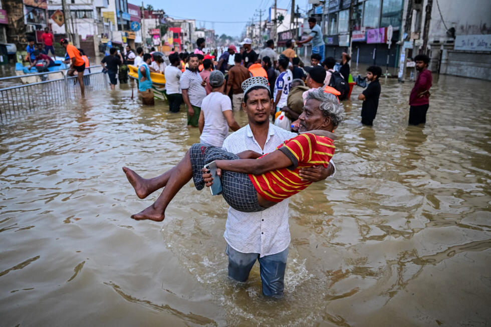 A young man carries an elderly man through a flooded street after heavy rains in Wellampitiya, a suburb of Colombo.