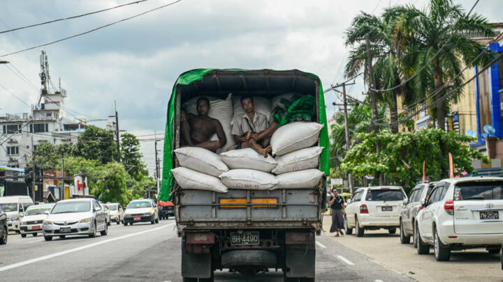 Workers sit in the back of a truck transporting goods in Yangon on August 5, 2025.