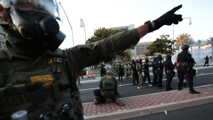 A US Border Patrol agent gestures near another arresting a protester near the United States Citizenship and Immigration Services (USCIS) Santa Ana Field Office.