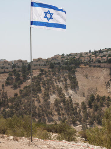 Una bandera israelí ondea, mientras se ve al fondo parte del asentamiento israelí de Maale Adumim, en Cisjordania ocupada por Israel, el 14 de agosto de 2025.