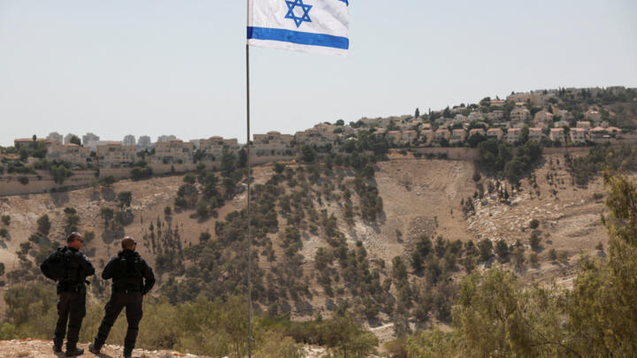 Una bandera israelí ondea, mientras se ve al fondo parte del asentamiento israelí de Maale Adumim, en Cisjordania ocupada por Israel, el 14 de agosto de 2025.