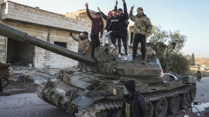 Syrian opposition supporters celebrate on top of a captured Syrian army tank in Maarat al-Numan, southwest of Aleppo, on November 30, 2024.