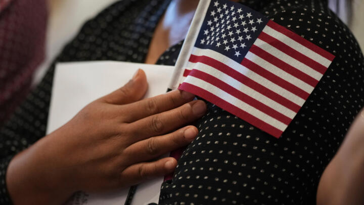 A woman clutches a US flag as she and applicants from other countries prepare to take the oath of citizenship in commemoration of Independence Day during a Naturalisation Ceremony in San Antonio, July 3, 2025.
