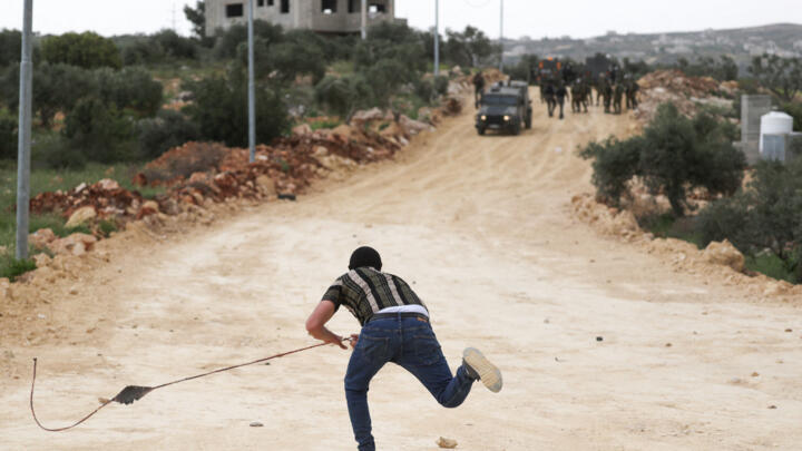 A Palestinian protester throws a rock at Israeli soldiers during a protest in the village of Beita, south of Nablus in the occupied West Bank, on April 10, 2023, against a march by settlers to the nearby Israeli outpost of Eviatar.