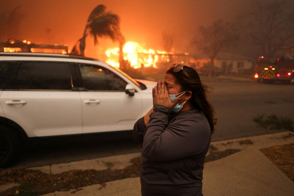 Una mujer reacciona mientras evacúa tras los fuertes vientos que avivan los devastadores incendios forestales en el área de Los Ángeles, en el incendio Eaton en Altadena, California, EE. UU., el 8 de enero de 2025.