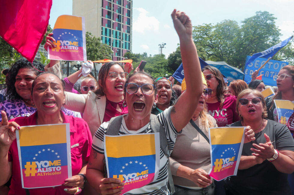 Venezolanos hacen gestos antes de alistarse en la Milicia Nacional Bolivariana tras el llamamiento a la reclutamiento nacional del presidente Nicolás Maduro, en medio de las crecientes tensiones con Estados Unidos por el despliegue de buques de guerra estadounidenses en la región, frente a un punto de alistamiento en Valencia, Venezuela, el 29 de agosto de 2025.