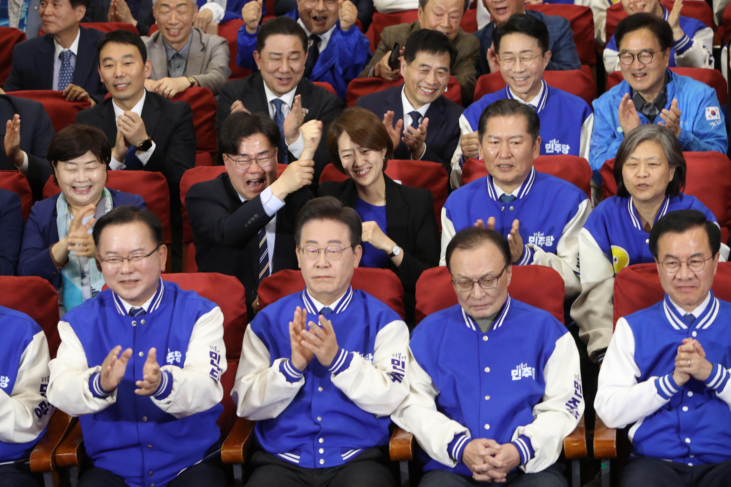 Le chef du Parti démocrate (DP), Lee Jae-myung (2e g), et ses candidats regardent les télévisions diffusant les résultats des sondages à la sortie des urnes pour les élections législatives, à l'Assemblée nationale, le 10 avril 2024 à Séoul, en Corée du Sud