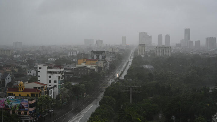 A few vehicles drive along an almost empty road amid heavy rain and strong winds in Vinh city, Nghe An province, on August 25, 2025, after Typhoon Kajiki made landfall.
