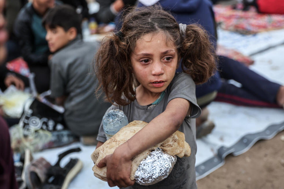 Une fillette palestinienne porte de la nourriture tandis que des personnes se rassemblent pour un repas de rupture du jeûne du ramadan à Beit Lahia, dans le nord de la bande de Gaza, le 15 mars 2025