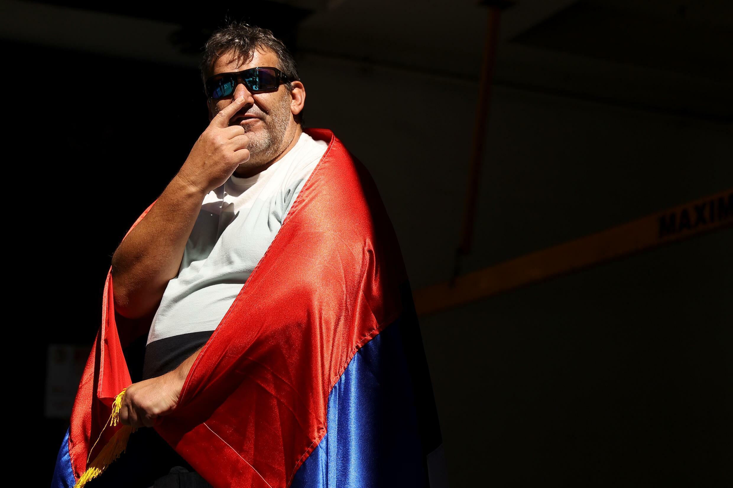 In Melbourne, January 16, 2022, wrapped in a Serbian flag, a fan of Novak Djokovic waits outside the player's lawyer's office.