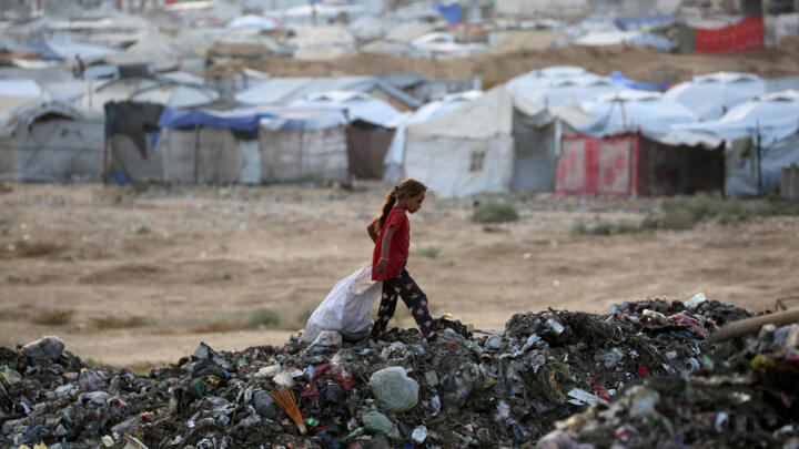 A girl sifts through the rubbish near tents and makeshift shelters at the Bureij camp for Palestinian refugees in the central Gaza Strip on September 21, 2025.