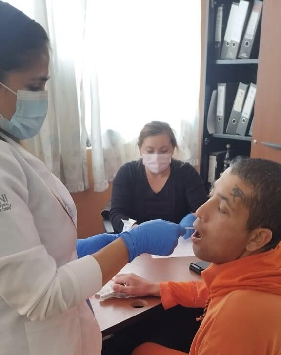 Personal forense y administrativo toma la muestra genética con hisopado bucal a una persona privada de la libertad en una cárcel ecuatoriana.