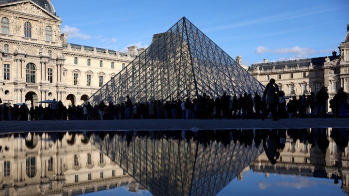 People stand outside the Louvre Museum, after French police arrested suspects in the Louvre heist case, in Paris, France on October 26, 2025.