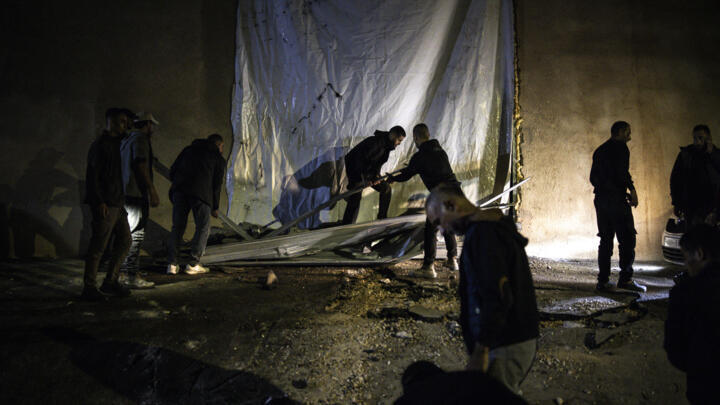 People help clean the site of a shooting that left two Palestinians dead during an Israeli operation in the West Bank city of Jenin on November 27, 2025.