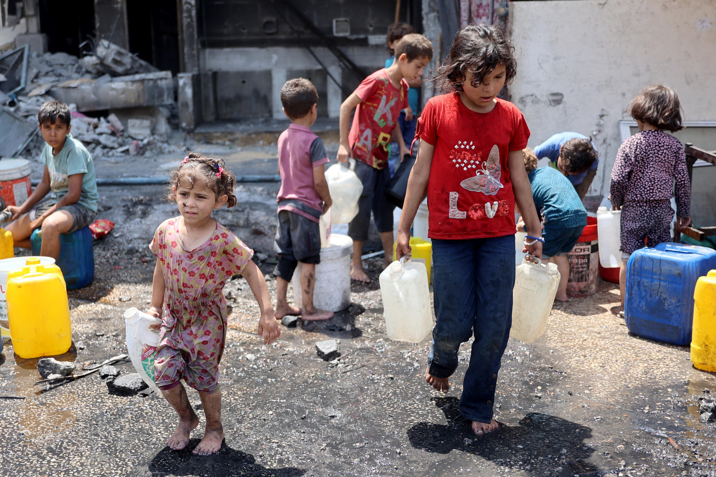 Des enfants remplissent des bidons d'eau dans le camp palestinien en ruines de Jabalia, dans le nord de la bande de Gaza, le 3 juin 2024