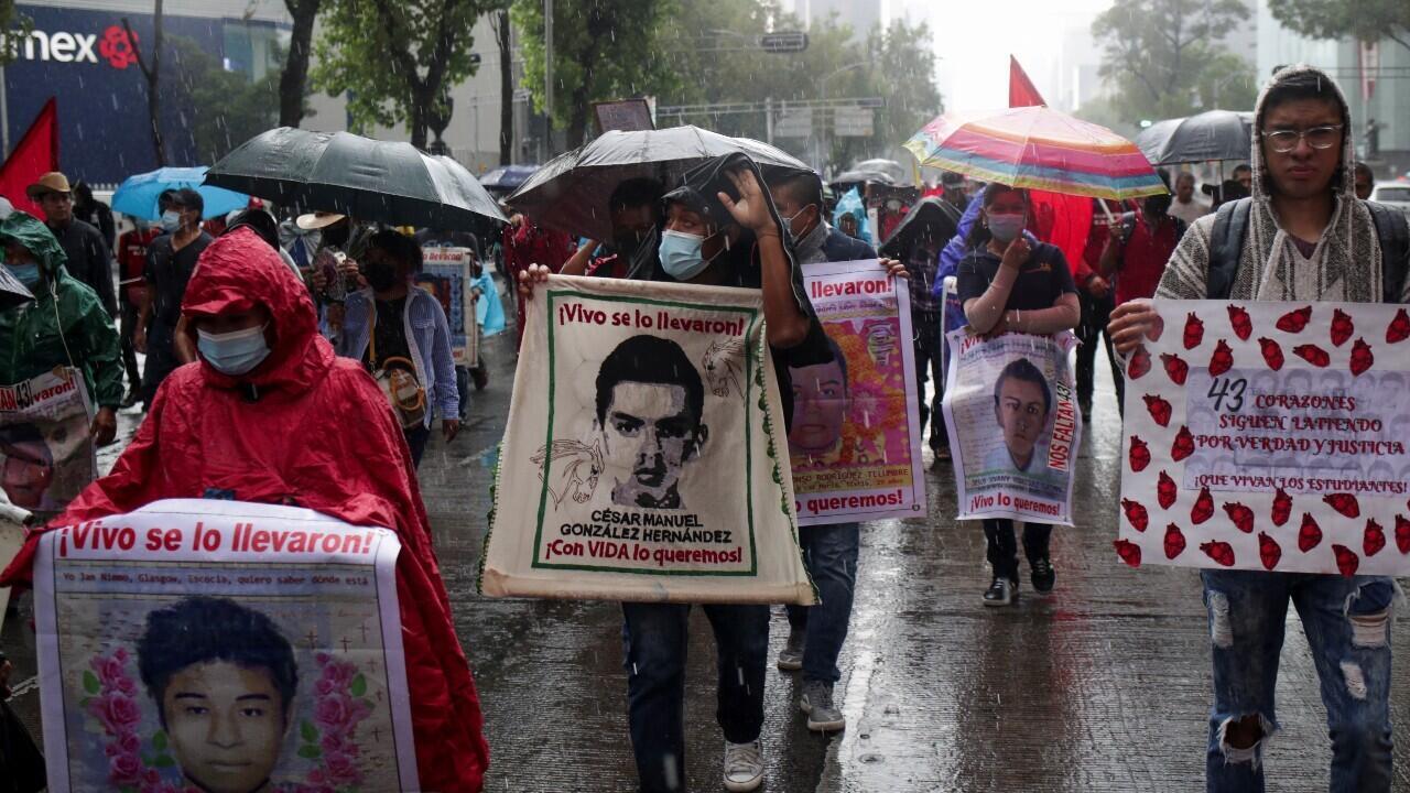 Familiares y manifestantes sostienen pancartas con imágenes de los estudiantes desaparecidos de la Escuela de Formación de Maestros de Ayotzinapa, mientras participan en una marcha para exigir justicia para sus seres queridos, en medio de fuertes lluvias, en Ciudad de México, México, el 26 de agosto de 2022