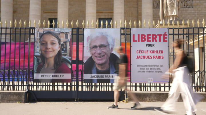 Des passants devant les portraits de Cécile Kohler, 40 ans, à gauche, et Jacques Paris, 72 ans, emprisonnés depuis plus de trois ans en Iran, installés devant l'Assemblée nationale française à Paris,