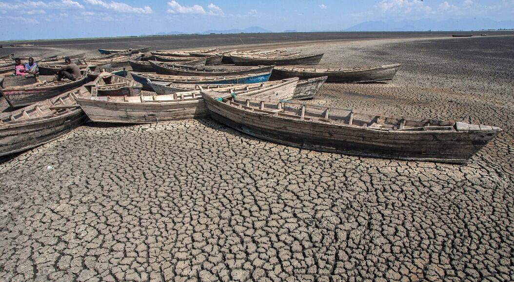 Archivo-Hombres sentados en botes estacionarios sin motor que yacen inactivos en el puerto seco de la isla Chisi del lago Chilwa en el interior del distrito de Zomba, al este de Malawi, en medio del aumento de la temperatura global, del nivel del mar y la intensificación de los eventos del clima extremos. Imagen tomada el 18 de octubre de 2018.