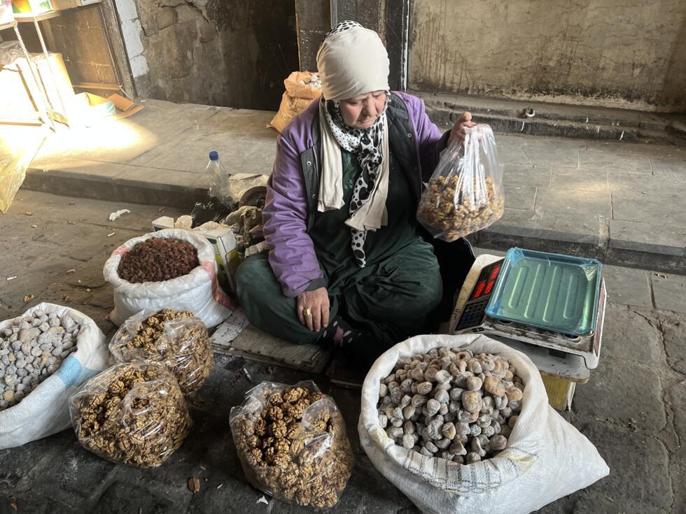 Les vendeurs à la sauvette sont nombreux comme cette Syrienne qui propose notamment des noix dans le souk Hamidieh à Damas le 14 janvier 2025.