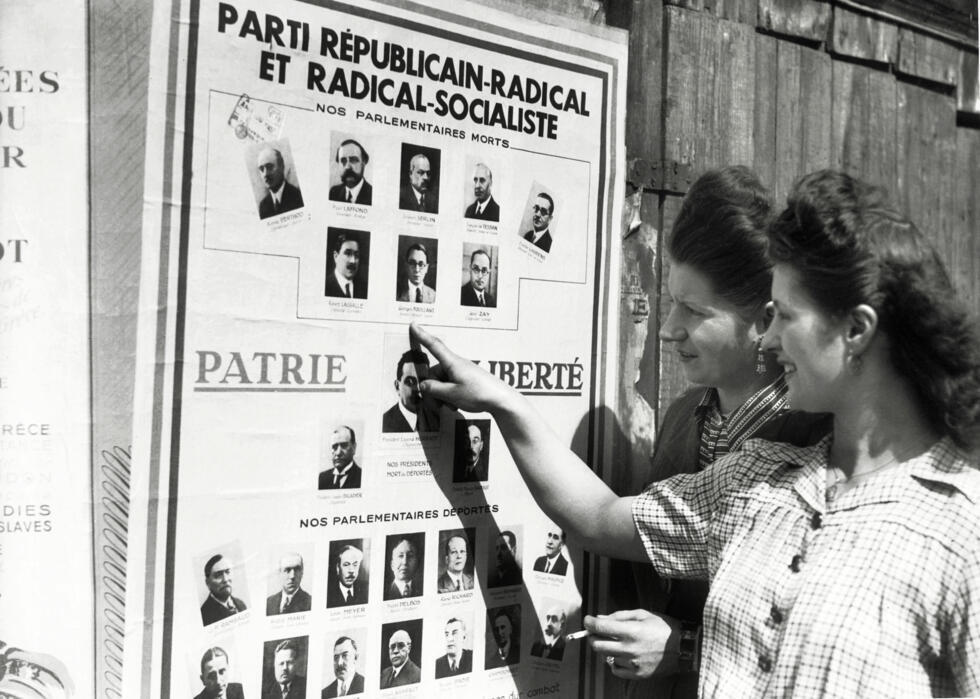 Des femmes devant une affiche électorale pour les élections municipales, avant de voter pour la première fois en France, le 29 avril 1945 à Paris.