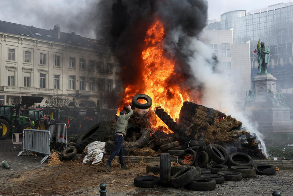Protesters burn tyres on a square near the European Parliament in Brussels on December 18, 2025.