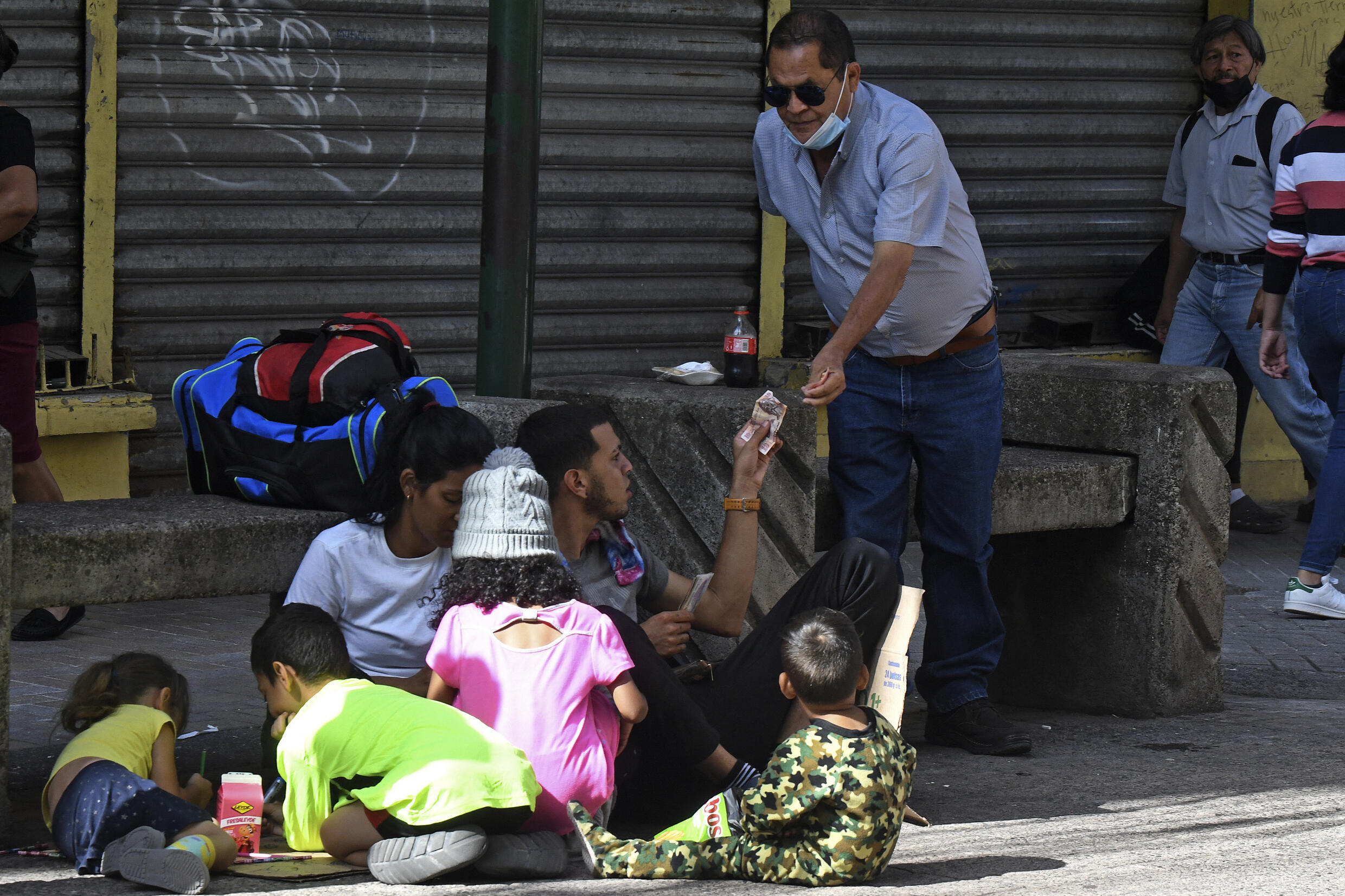 Un hombre da dinero a una familia de migrantes venezolanos en el Paseo Liquidambar de Tegucigalpa, el 13 de octubre de 2022.