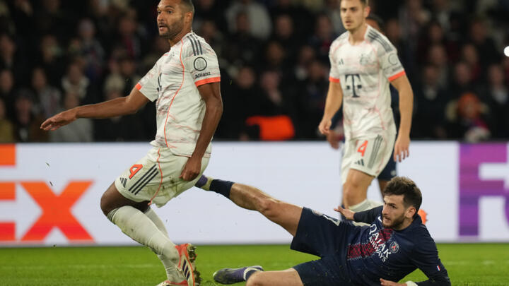 PSG's Khvicha Kvaratskhelia, bottom, lies on the ground besides Bayern's Jonathan Tah during the Champions League opening phase soccer match between Paris Saint-Germain and Bayern Munich in Paris.