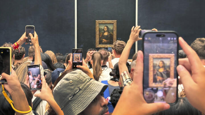 Tourists jostle take a photograph of Leonardo da Vinci's painting of the Mona Lisa at the Louvre Museum in Paris, France, Wednesday, August 8, 2024.