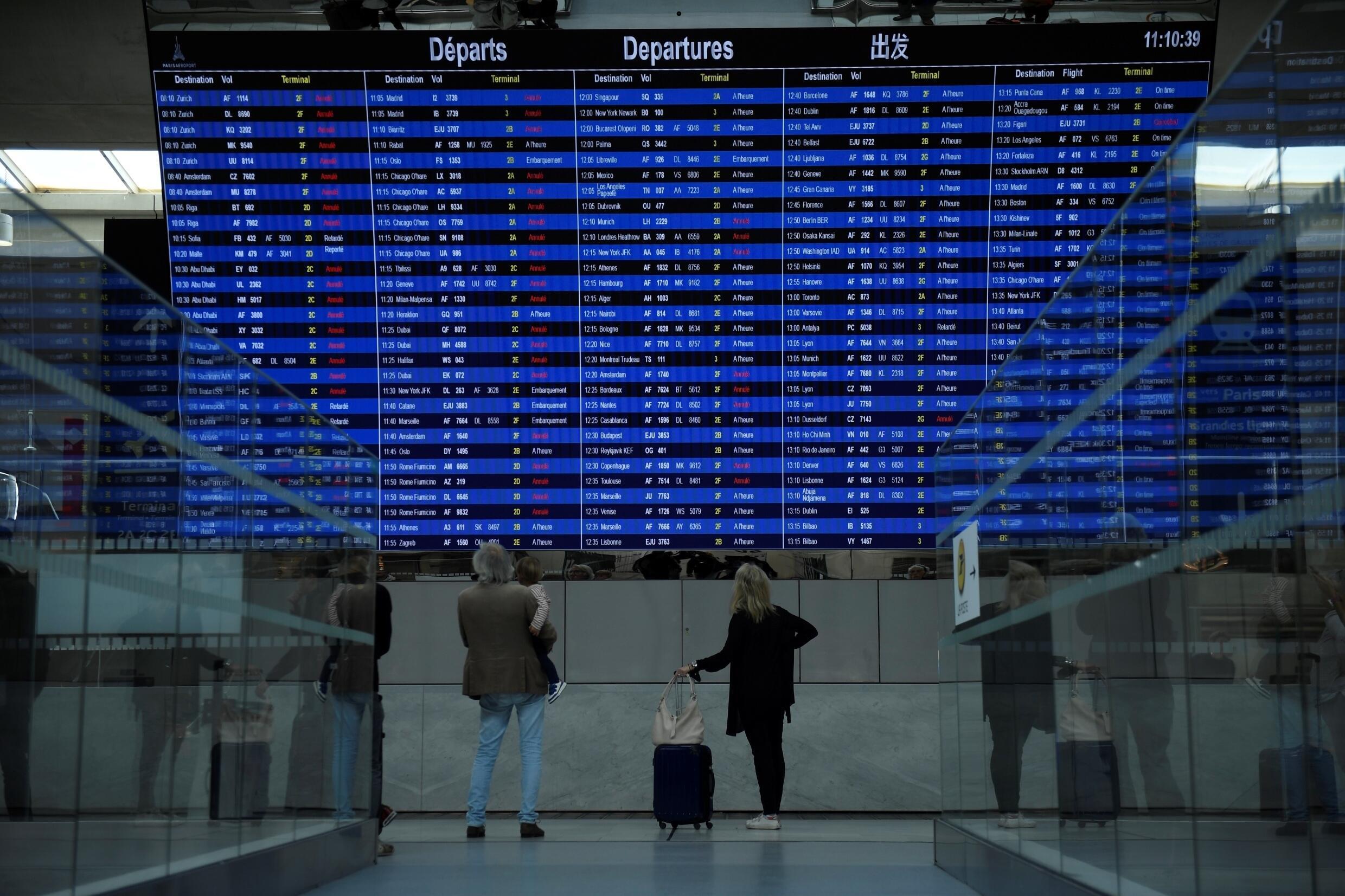 Des voyageurs consultent un tableau d' information sur les vols au départ de l'aéroport Roissy-Charles-de-Gaulle, le 16 septembre 2022