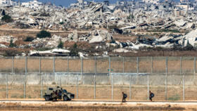 Israeli army soldiers walk towards an armoured vehicle at a position along the border fence with the Gaza Strip in southern Israel.