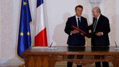 French President Emmanuel Macron (L) and Algeria's President Abdelmadjid Tebboune (C) attend a signing ceremony in the pavilion of honour at Algiers airport, in Algiers, on August 27, 2022.