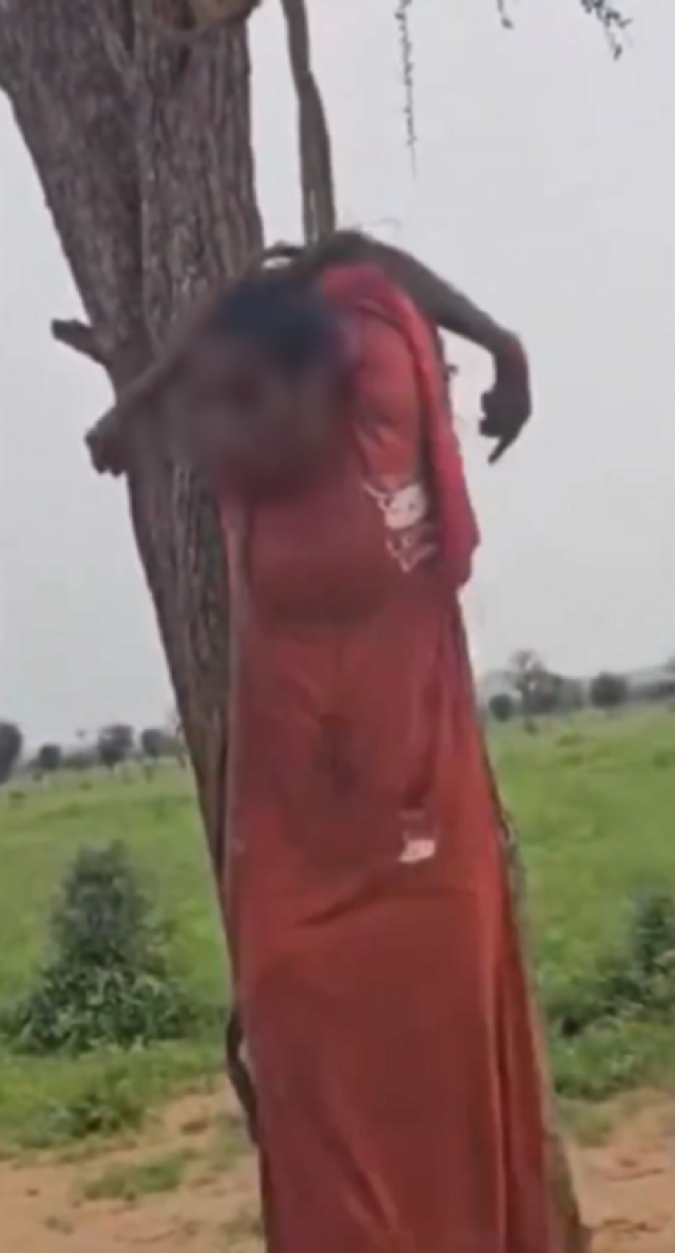 This is a screenshot of the video showing Qisma Ali Omar hanging from a tree. The victim’s face has been blurred by our team.