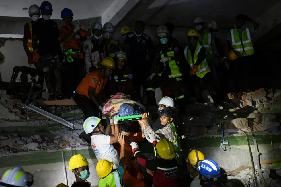 Rescue workers carry a victim trapped under the rubble of a destroyed building in Mandalay