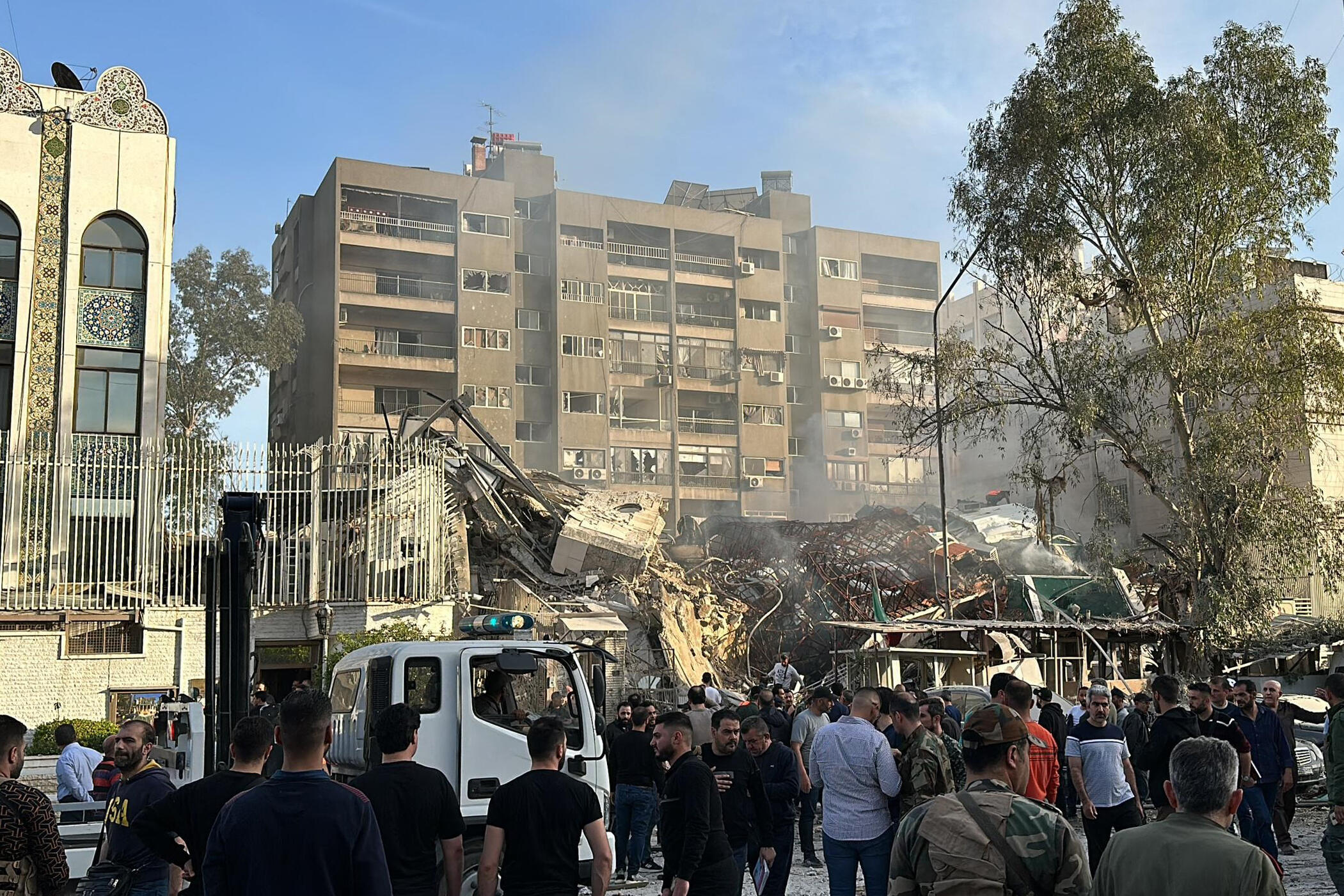 Une foule se rassemble à proximité de l'annexe de l'ambassade d'Iran en Syrie, soufflée par une frappe israélienne lundi 1er mars 2024.