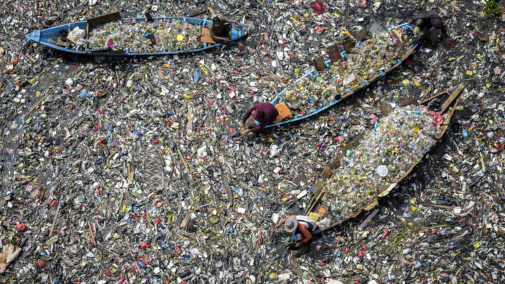 People on boats collect recyclable plastics from the heavily polluted Citarum River at Batujajar in Bandung, West Java, on June 12, 2024.