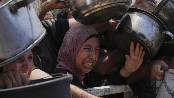 Palestinians struggle to get donated food at a community kitchen, in Gaza City, northern Gaza Strip, Saturday, July 26, 2025.